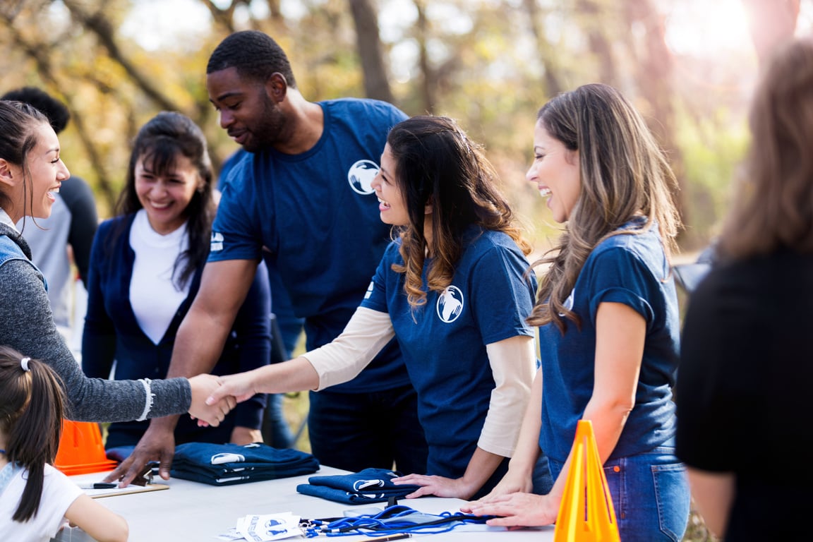 Women shake hands across event registration table