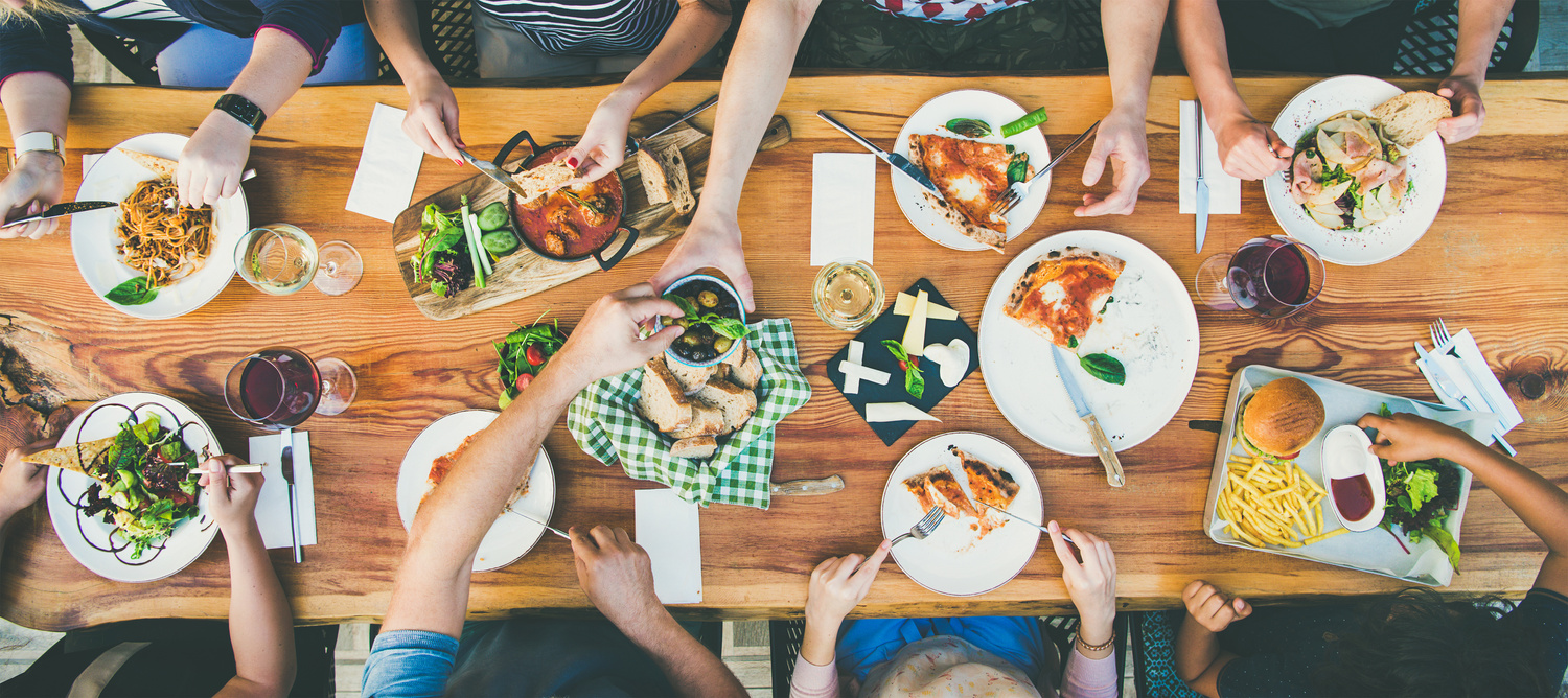 eating and leisure concept - group of people having dinner at table with food